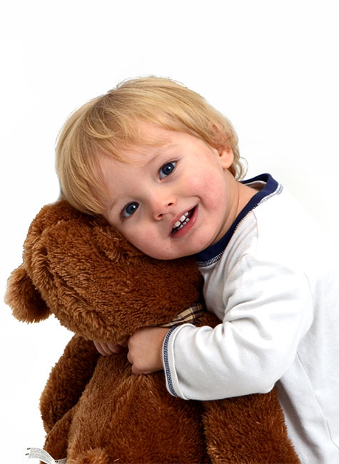 Smiling toddler hugging his teddy bear